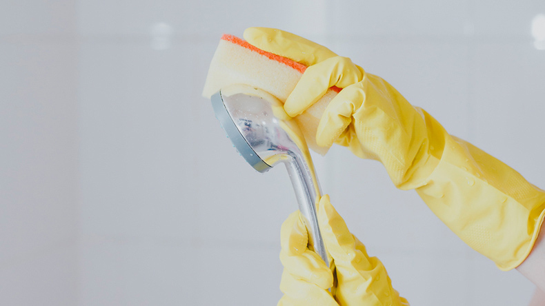 cleaning a shower head with sponge